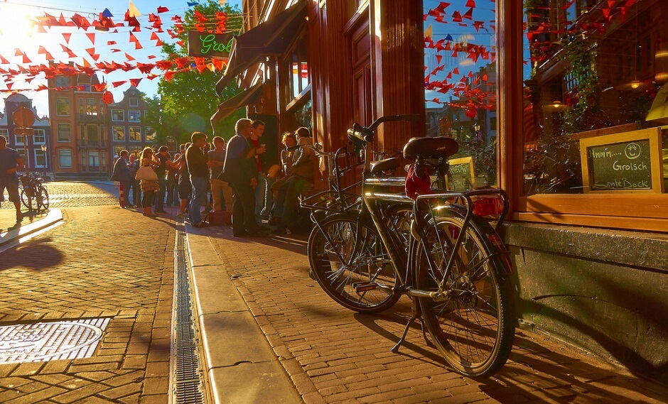 Vue d'une rue d'Amsterdam avec un vélo garé devant un café.